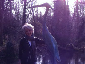 A photo of Joanna standing next to a statue of a heron in in The Watermill gardens