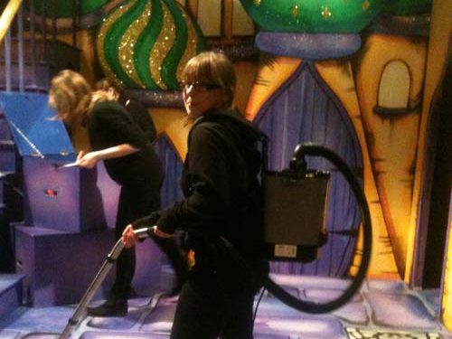 A photo of stage managers cleaning glitter after Arabian Nights